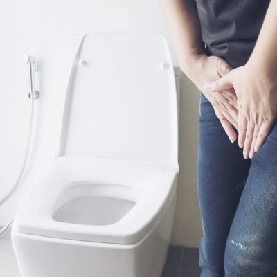 Woman holding hand near toilet bowl - health problem concept